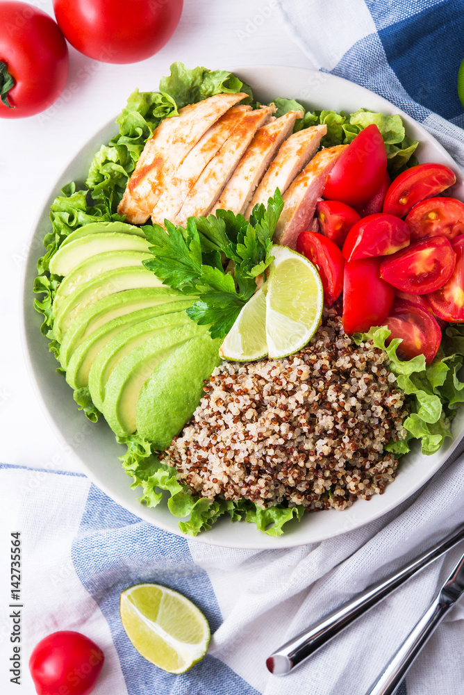 Plakat Healthy salad bowl with quinoa, tomatoes, chicken, avocado, lime and mixed greens (lettuce, parsley) on white wooden background top view. Food and health.