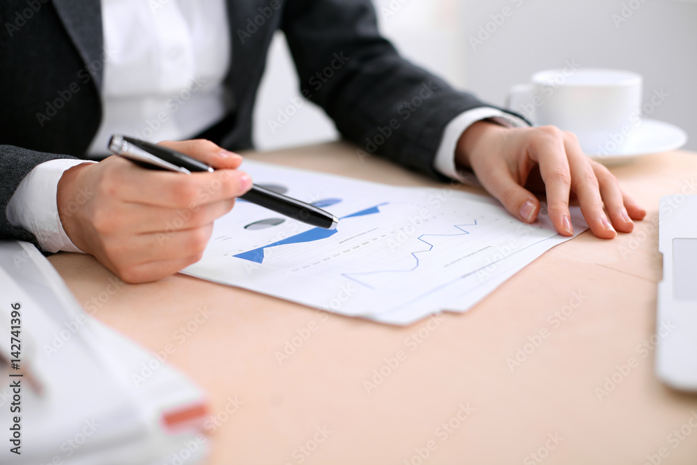 Fototapeta premium Business woman sitting at the table and examines the financial results