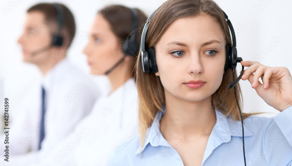 Call center operators. Focus at young beautiful business woman in headset. Call center operators. Focus at young beautiful business woman in headset.