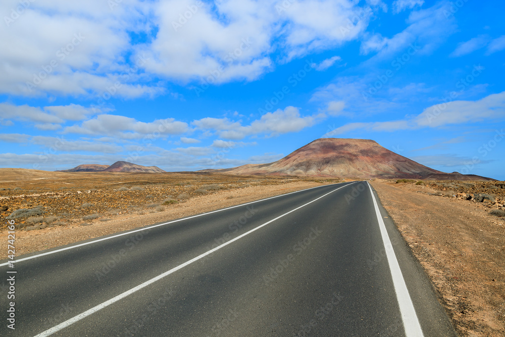 Road to Corralejo along desert with volcanoes, Fuerteventura, Canary Islands, Spain Road to Corralejo along desert with volcanoes, Fuerteventura, Canary Islands, Spain