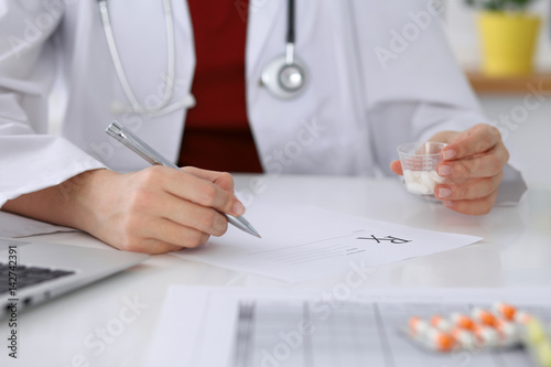 Female medicine doctor fills up  prescription form to patient closeup. Panacea and life save  prescribe treatment  legal drug store  contraception concept