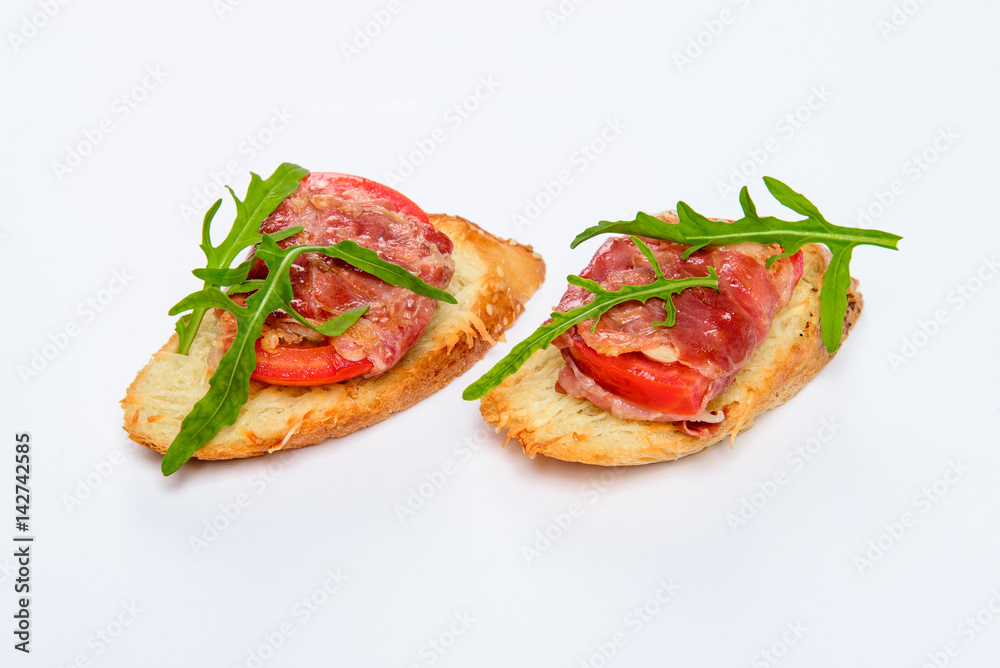 Two bruschettes with serrano ham, cheese and arugula