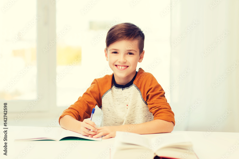 smiling student boy writing to notebook at home smiling student boy writing to notebook at home