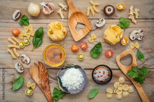 Italian foods concept and menu design.Various kind of pasta with ingredients sweet basil ,tomato ,garlic ,parsley ,champignon and extra virgin olive oil on wooden background flat lay.
