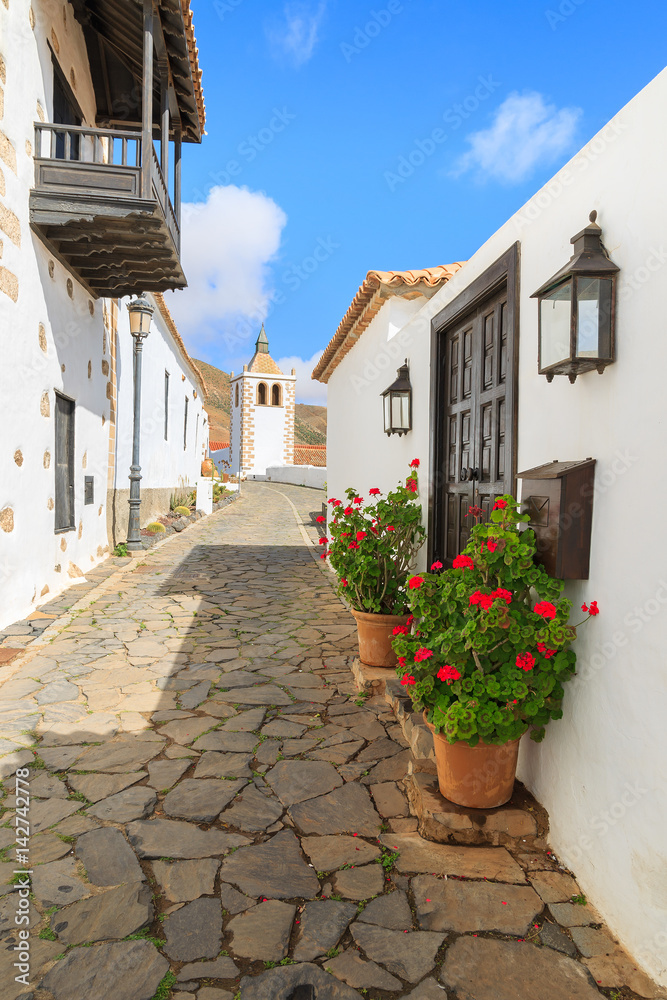 Narrow street in Betancuria village with Santa Maria church tower in background, Fuerteventura, Canary Islands, Spain
