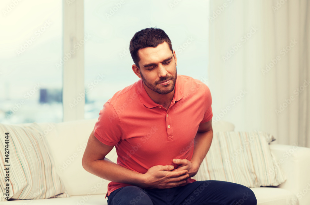 unhappy man suffering from stomach ache at home