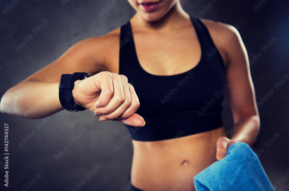 close up of woman with smartwatch and towel in gym close up of woman with smartwatch and towel in gym