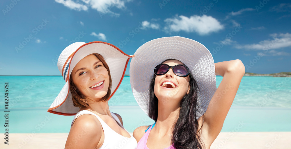 happy young women in hats on summer beach
