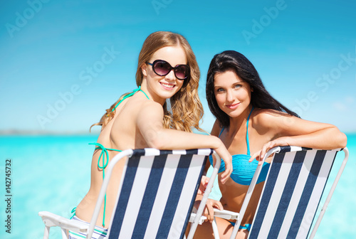 happy women sunbathing in chairs on summer beach