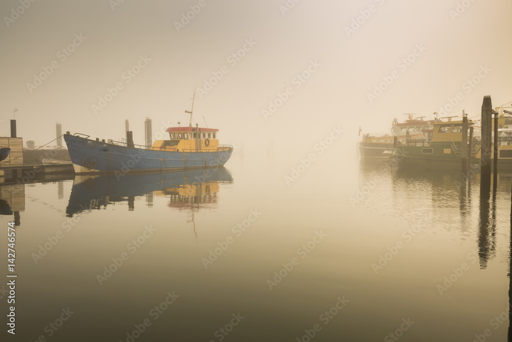 Fototapeta premium Fishing boats awaiting delayed departure in harbour due to heavy fog