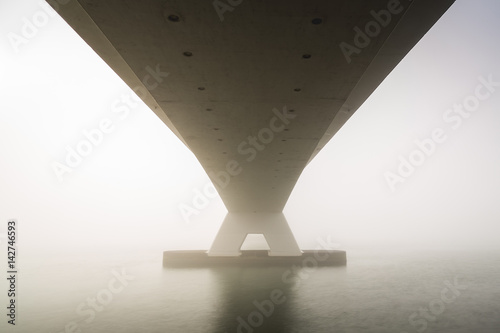 Low visibility due to heavy fog covering the Zeeland bridge, sunshine is visible at the background photo