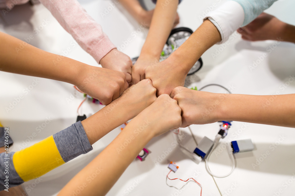 happy children making fist bump at robotics school