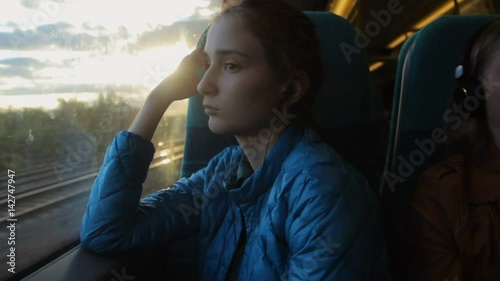 Young brunette hipster girl looking to the window in the train and thinking about her future.