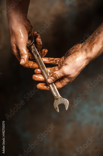 Mechanic. Dirty hands holding wrench. © tarasov_vl