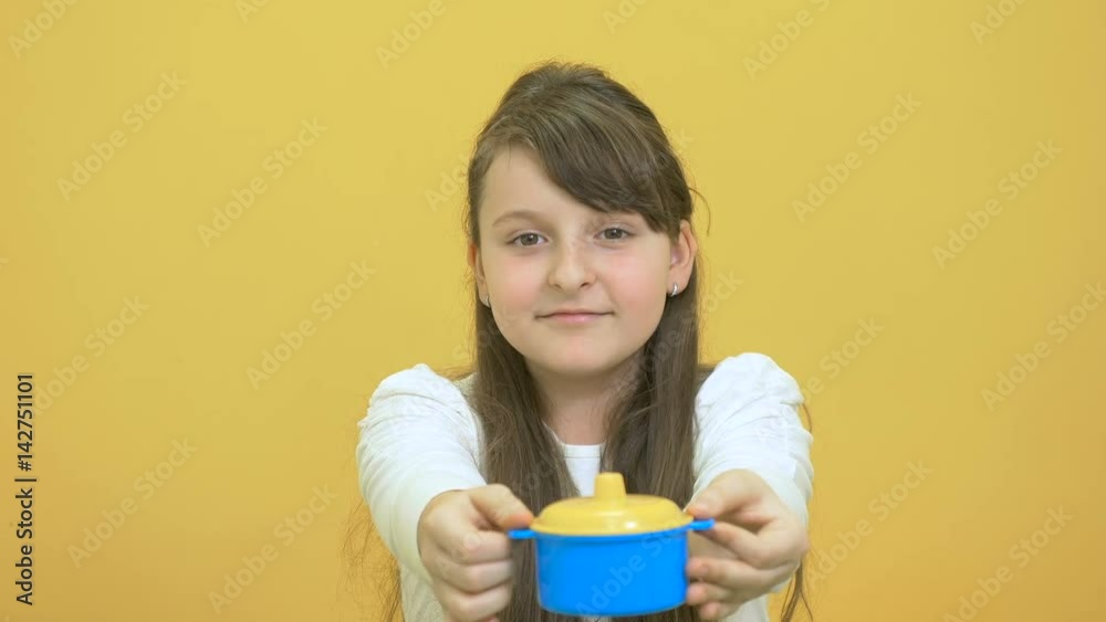Pretty little girl show a plastic pot on the yellow background
