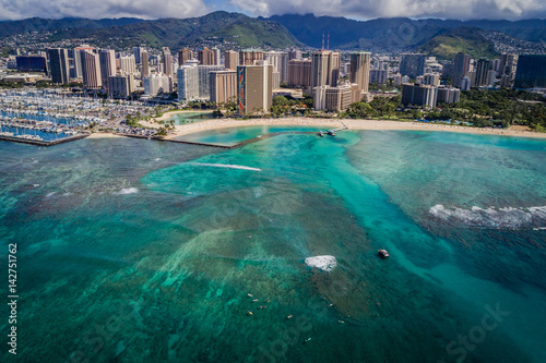 View surfers riding waves in ocean near beach in Hawaii 