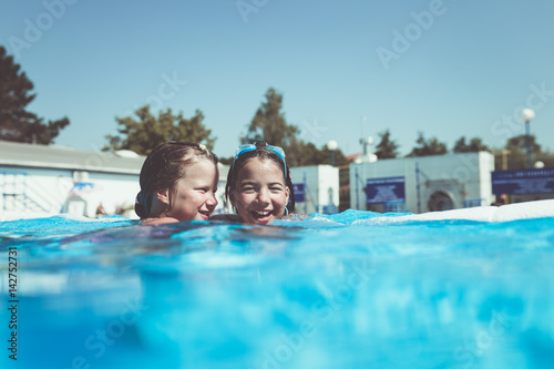 Underwater fun. Two cute little girls with goggles swimming underwater and diving in the swimming poll. Kids sport and leisure.