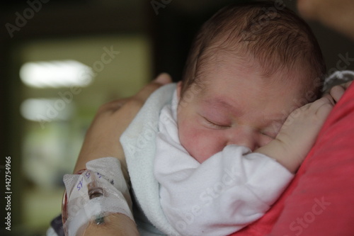 Newborn baby is in the arms of his mother on the hospital bed