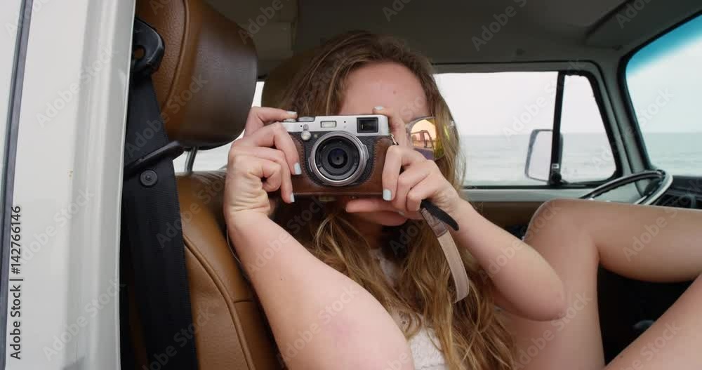 Portrait Beautiful hippie girl taking photos with retro digital camera road trip camper van