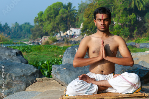 Canvas Print An Indian yogi meditating on a riverbank in India.