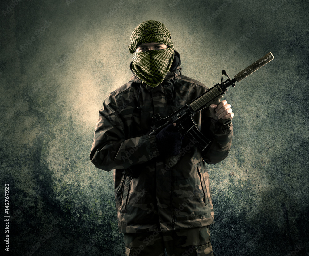 Portrait of a heavily armed masked soldier with grungy background