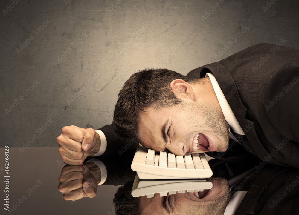 Obraz premium Frustrated businessman's head on keyboard