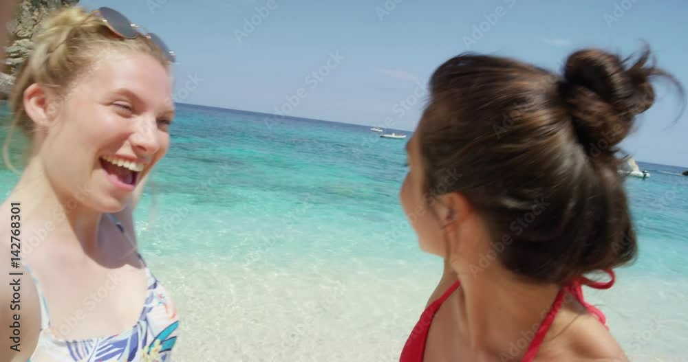 Best friends having video chat using smart phone on beach taking selfie photograph smiling blowing kiss waving enjoying tropical nature background view on  summer vacation travel adventure POV