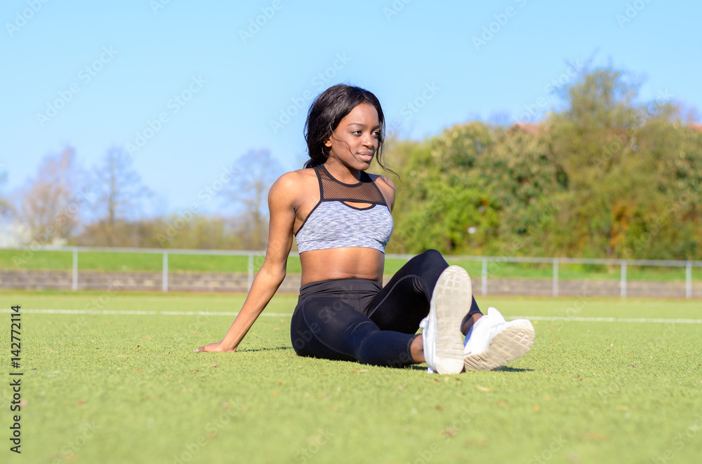 Fit athletic woman relaxing on a sports field Fit athletic woman relaxing on a sports field