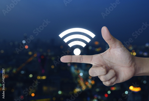 Wifi icon on finger over blur colorful night light city tower, Technology and internet concept