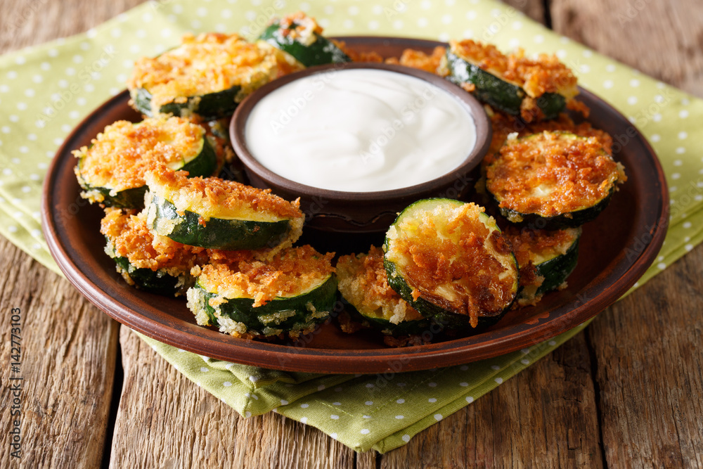 Homemade zucchini slices in breadcrumbs with sour cream close-up. horizontal