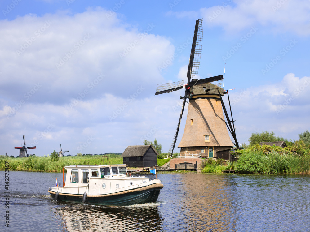 Sunny scenery with a small boat and ancient windmill, Kinderdijk, Netherlands.