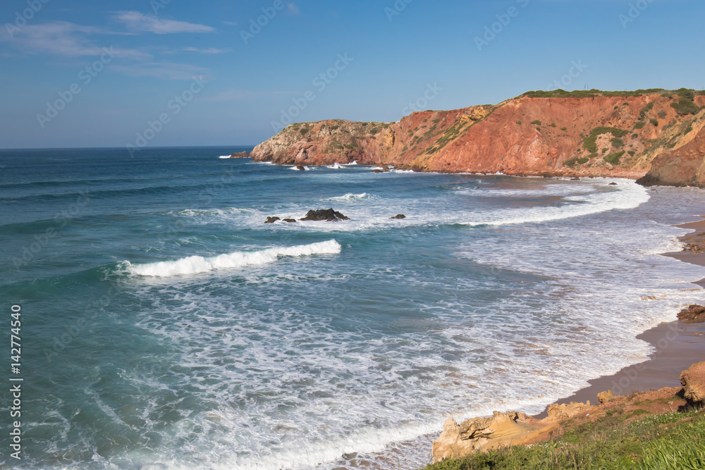 travel to colorful amado beach with waves on atlantic coastline, algarve, portugal 