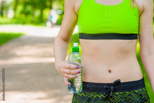 Close up woman stomach with hands holding water