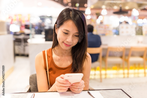 Woman using mobile phone in coffee shop