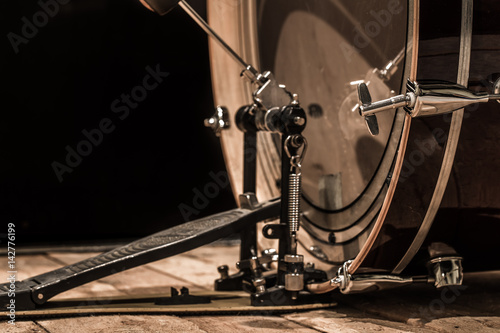 percussion instrument, bass drum with pedal on wooden boards with a black background