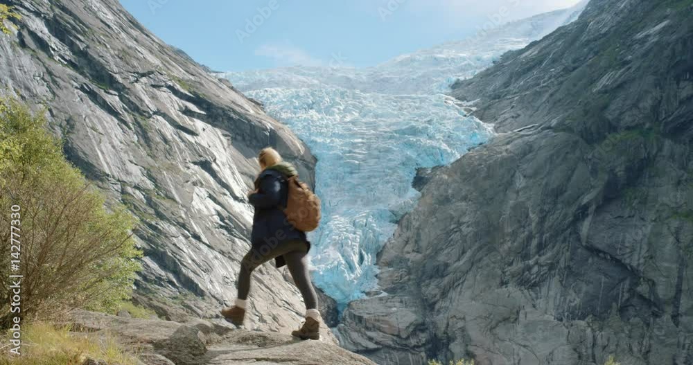 Climate change glacier melting Woman looking at glacial view Hiking Girl standing on rock scenic landscape enjoying vacation travel adventure nature Norway