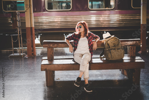 Young hipster woman waiting on the station platform with backpack. Travel concept.