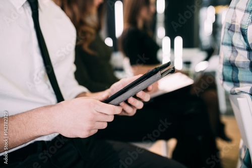 Close up of young man with tablet make notice at presentation or meeting of office team. Teamwork.