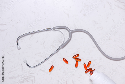 Capsules with stethoscope on table. Flat lay.