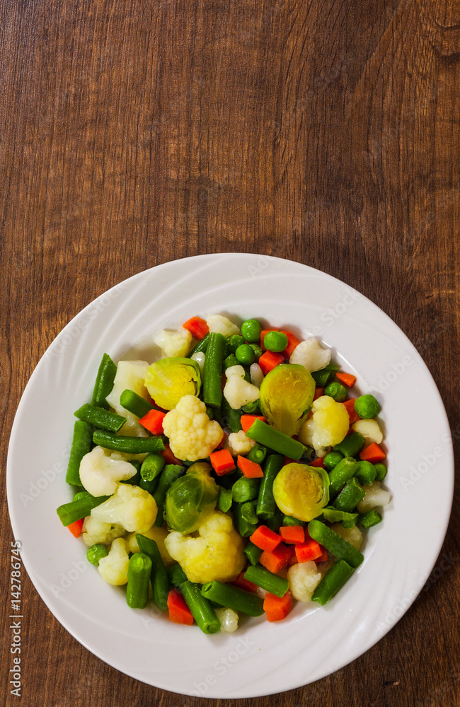 Mixed vegetables on a plate on wooden table with copy space. top view