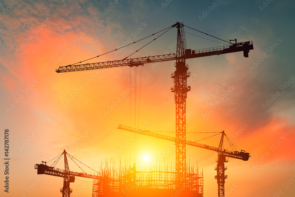 Crane and building construction site at sunset Crane and building construction site at sunset