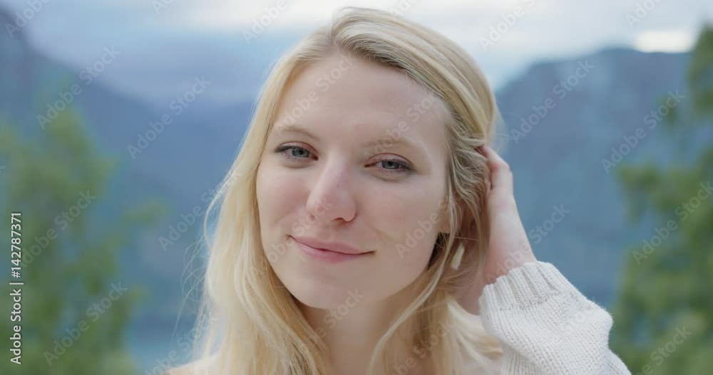 Close up portrait of beautiful young woman smiling in nature background Girl standing at top of mountain in front of Fjords Norway slow motion Close up portrait of beautiful young woman smiling in nature background Girl standing at top of mountain in front of Fjords Norway slow motion