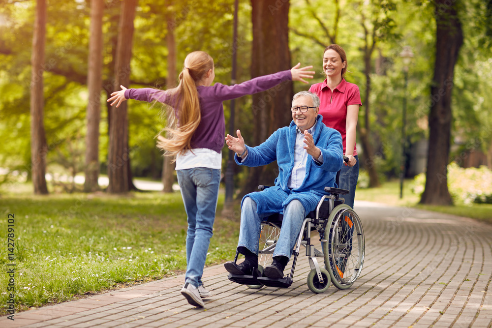 disabled grandfather in wheelchair welcoming his granddaughter. disabled grandfather in wheelchair welcoming his granddaughter.
