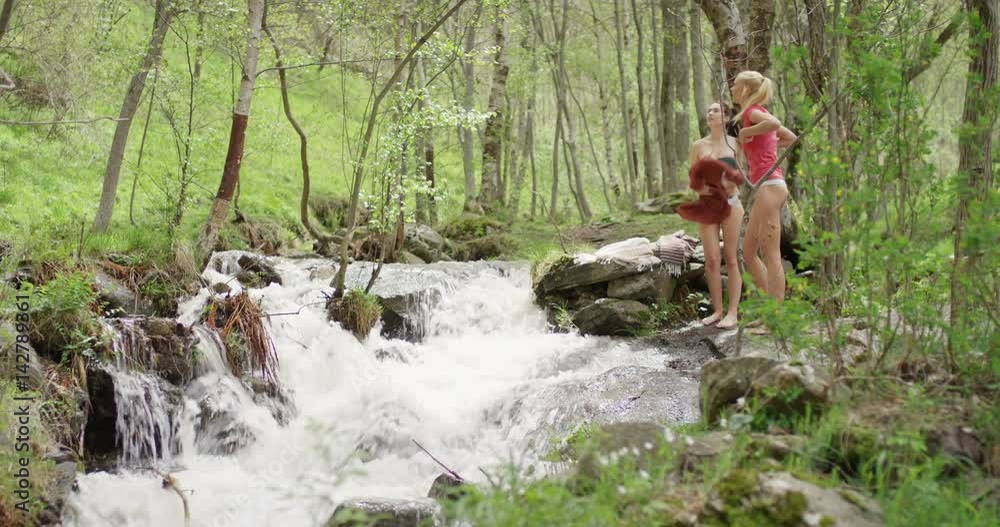 Two young women best friends swimming in river outdoors ...    