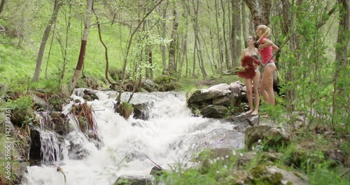 Two young women best friends swimming in river  outdoors undressing in nature carefree girls enjoying adventure vacation