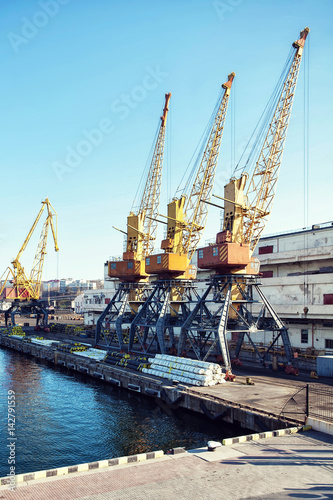 Port cargo crane over blue sky background. Sea port, crane for loading at sunset. Transportation