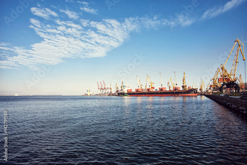 Port cargo crane over blue sky background. Sea port, crane for loading at sunset. Transportation