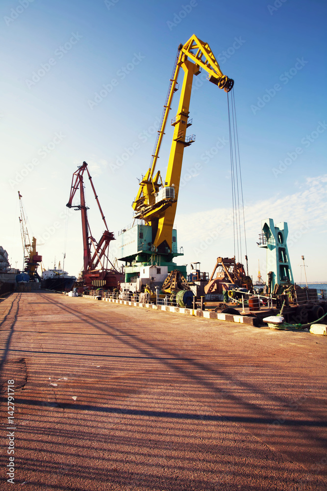 Port cargo crane over blue sky background. Sea port, crane for loading at sunset. Transportation