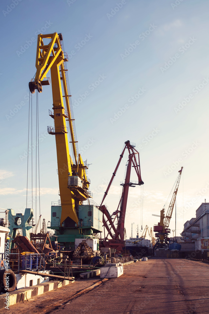 Port cargo crane over blue sky background. Sea port, crane for loading at sunset. Transportation