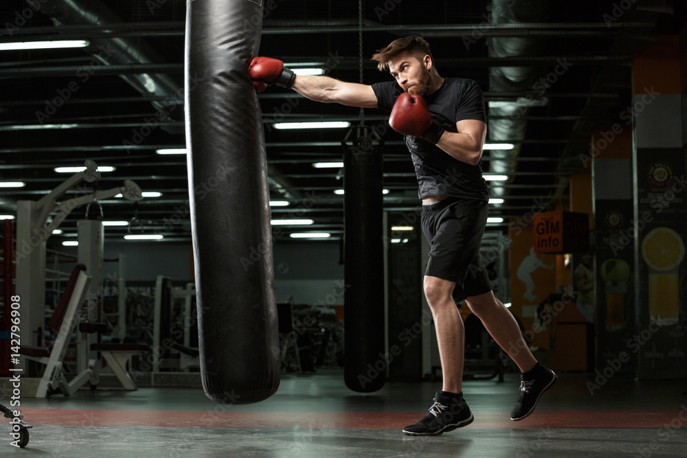 Concentrated young strong sports man boxer make exercises